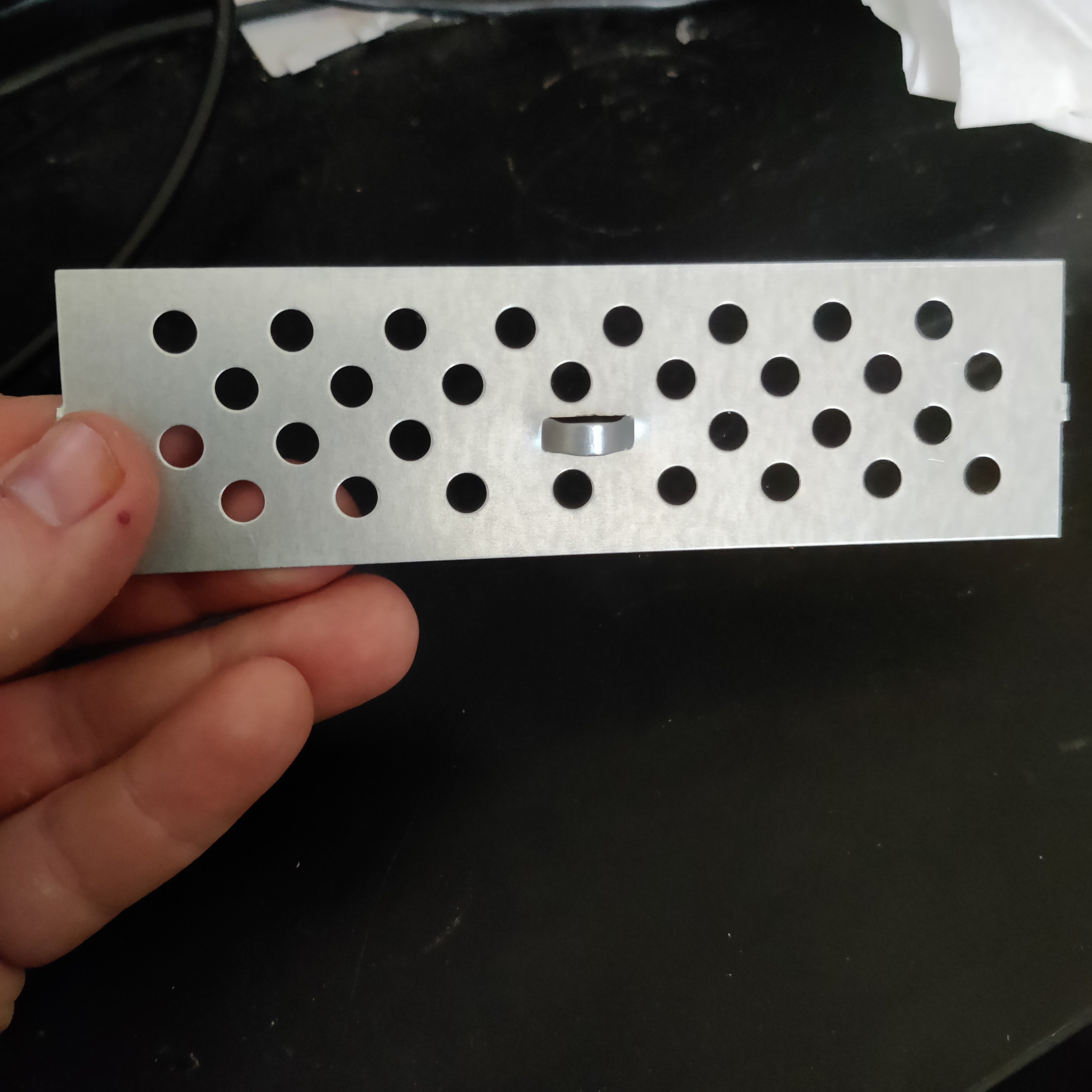 A hand showing a metal rectangular cutout from the case