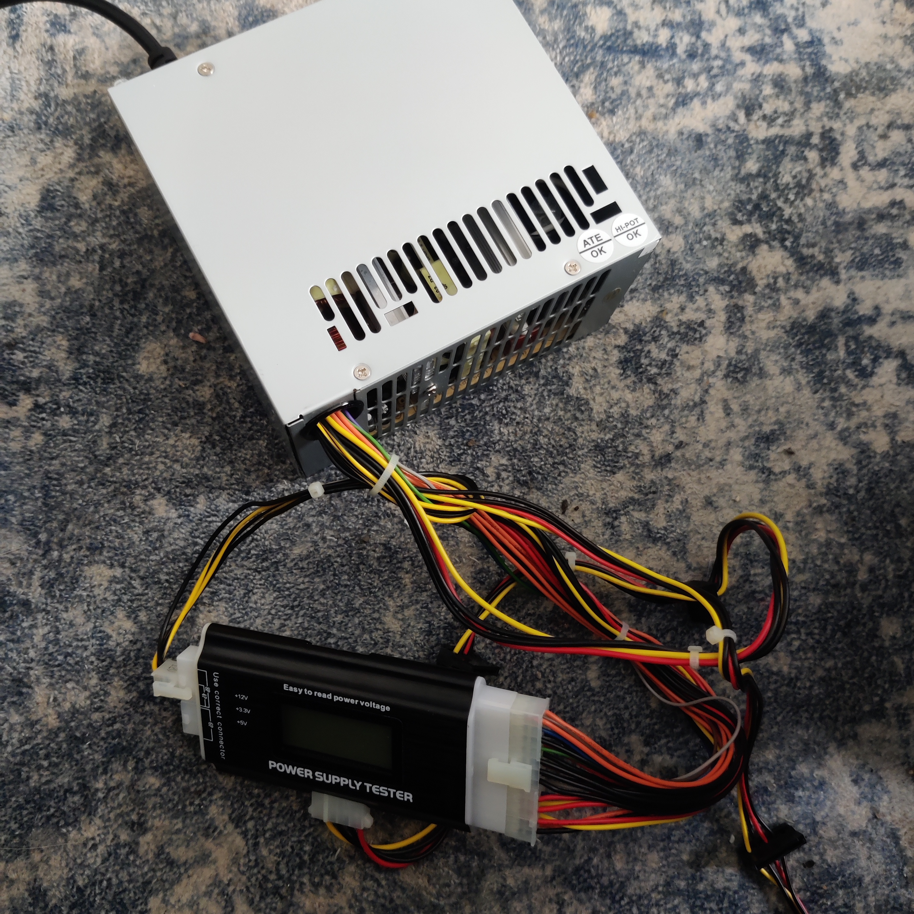 An image of a silver coloured PSU showing nothing on a power supply tester
